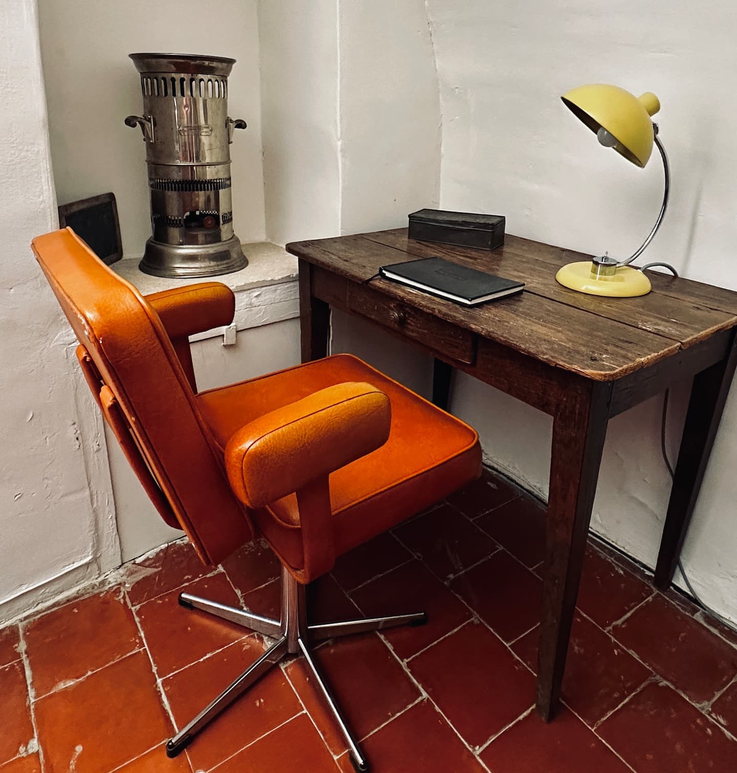 Un pupitre d'écolier et une chaise orange devant la fenêtre
