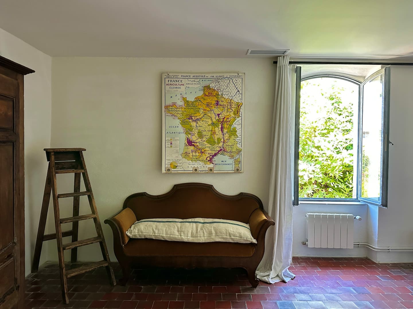 Chambre avec banquette ancienne et carte de France murale