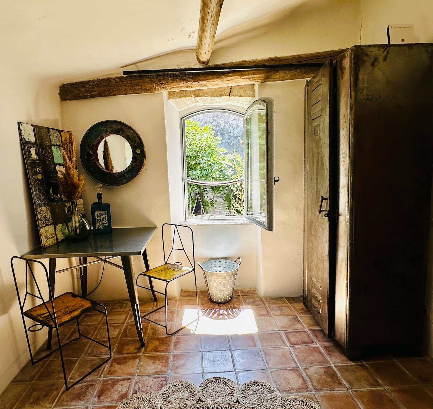 Coin table et chaises devant une porte ancienne, sol en tomettes